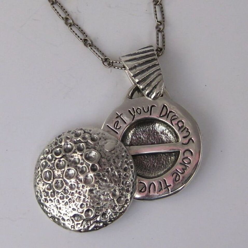 Dream Locket in sterling silver has a highly textured moon image on the front and opens to reveal the inscription 